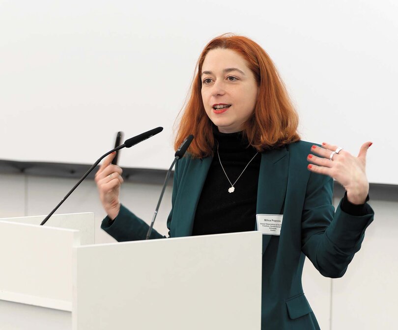 Milica Popović gestures with her hands at the lectern