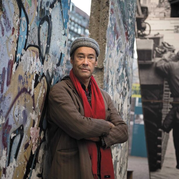Porträtfoto von Thomas Krüger mit Mütze und Schal vor der Berliner Mauer